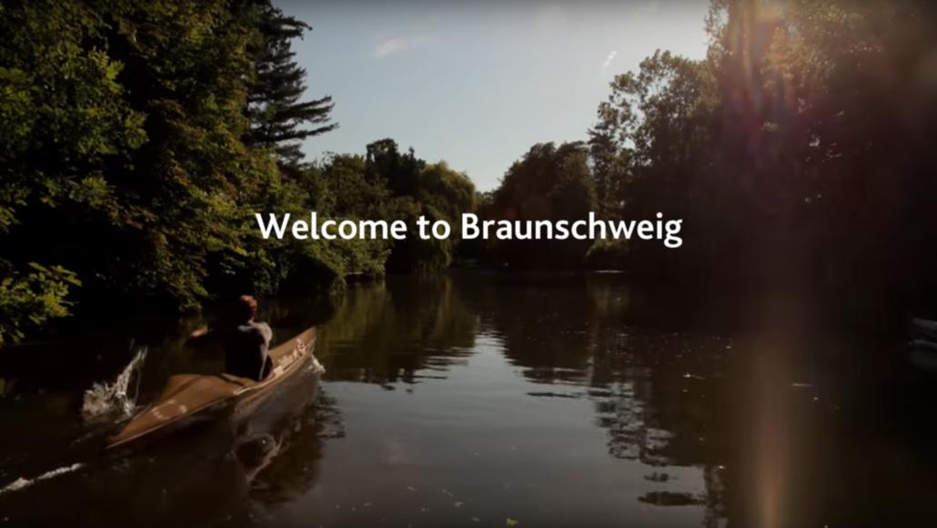 Eine Person fährt in einem Kajak über die Oker. Im Vordergrund steht: "Welcome to Braunschweig".