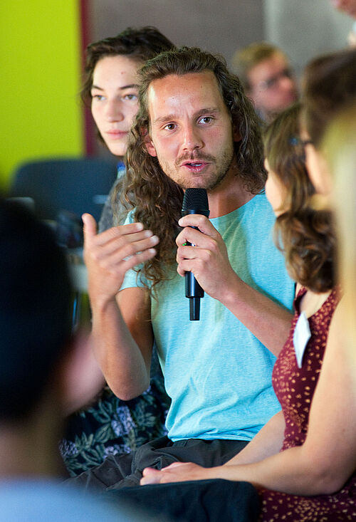 Tobi Rosswog spricht bei einer öffentlichen Veranstaltung in ein Mikrofon.