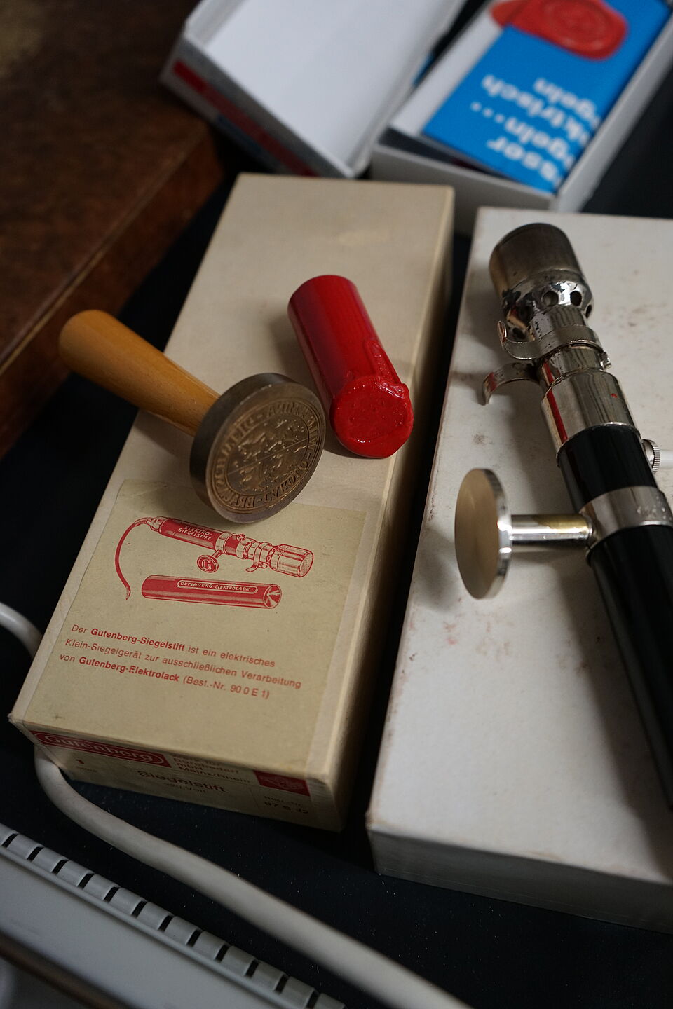 An old seal of the TU Braunschweig with an electric sealing pin and the necessary sealing wax.