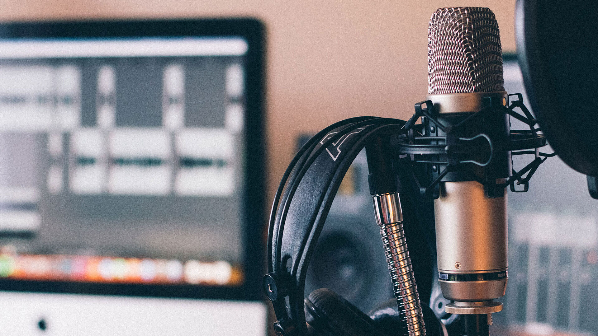 Microphone with headphones and a PC in the background.