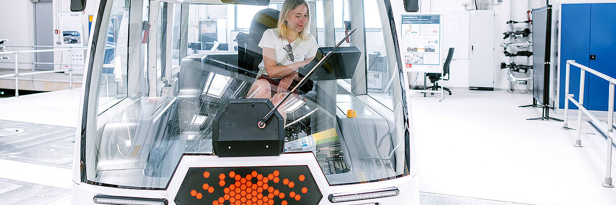 Frau sitzt in einem Forschungsfahrzeug im NFF-Technikum 