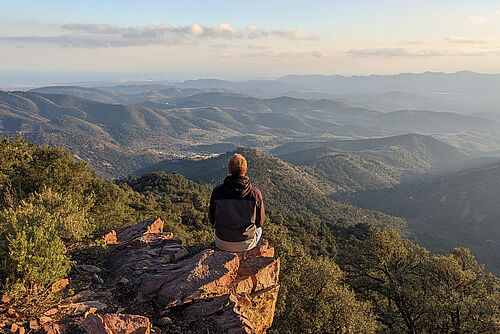  A man sits on a cliff in the Parc Natural de la Serra d'Espadà.