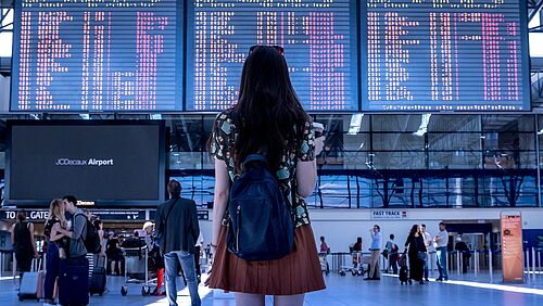 Eine Frau steht vor einer Anzeigetafel am Flughafen