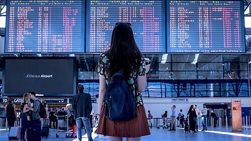 A woman is standing in front of a display board at the airport