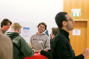 Conference participants stand together at a bar table and chat.