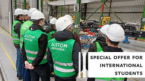 Eine Gruppe von Besucher*innen mit Warnwesten und Helmen im Alstom-Werk.