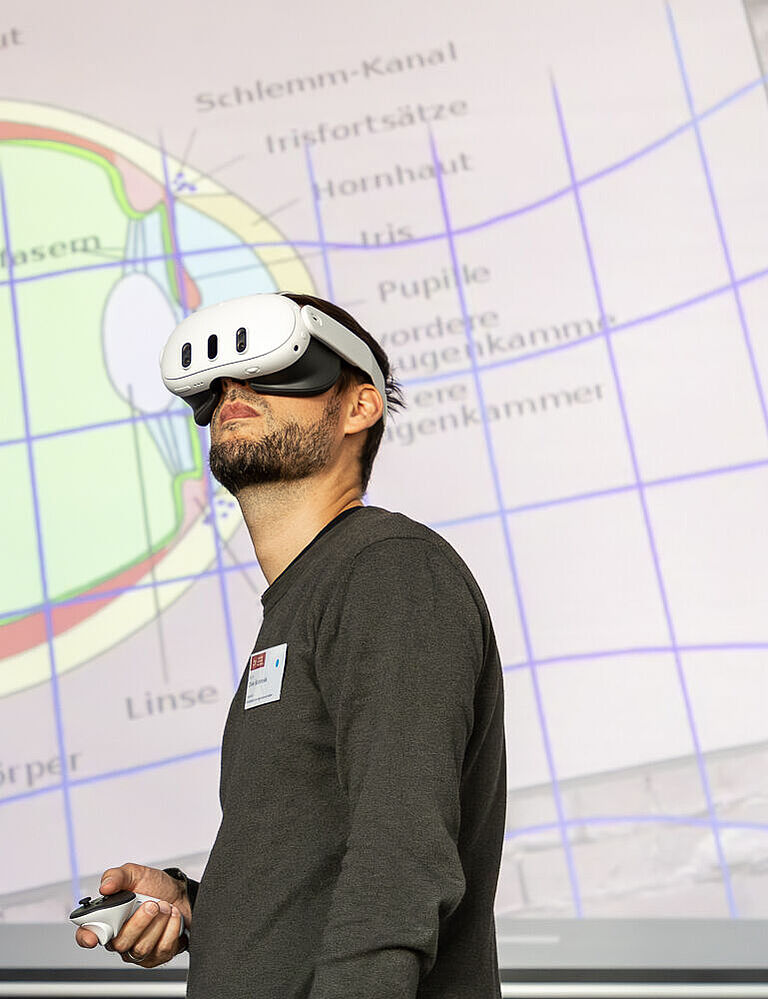 Ein Mann mit VR-Brille vor der Projektion einer schematischen Darstellung eines Augues