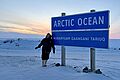 Emma Cameron vor dem berühmten Schild am Arktischen Ozean in Tuktoyaktuk, Nordwest-Territorien. 
