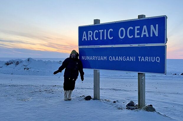 Emma Cameron vor dem berühmten Schild am Arktischen Ozean in Tuktoyaktuk, Nordwest-Territorien. 