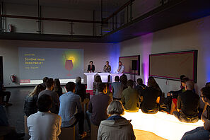 Drei Personen halten einen Vortrag über die Arbeitswelt.