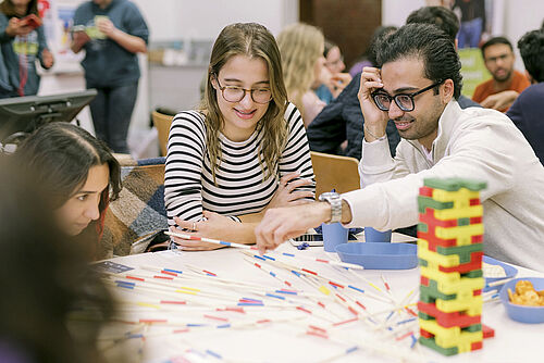 Internationale Studierende spielen während des Sprachcafés gemeinsam Spiele und lachen dabei.