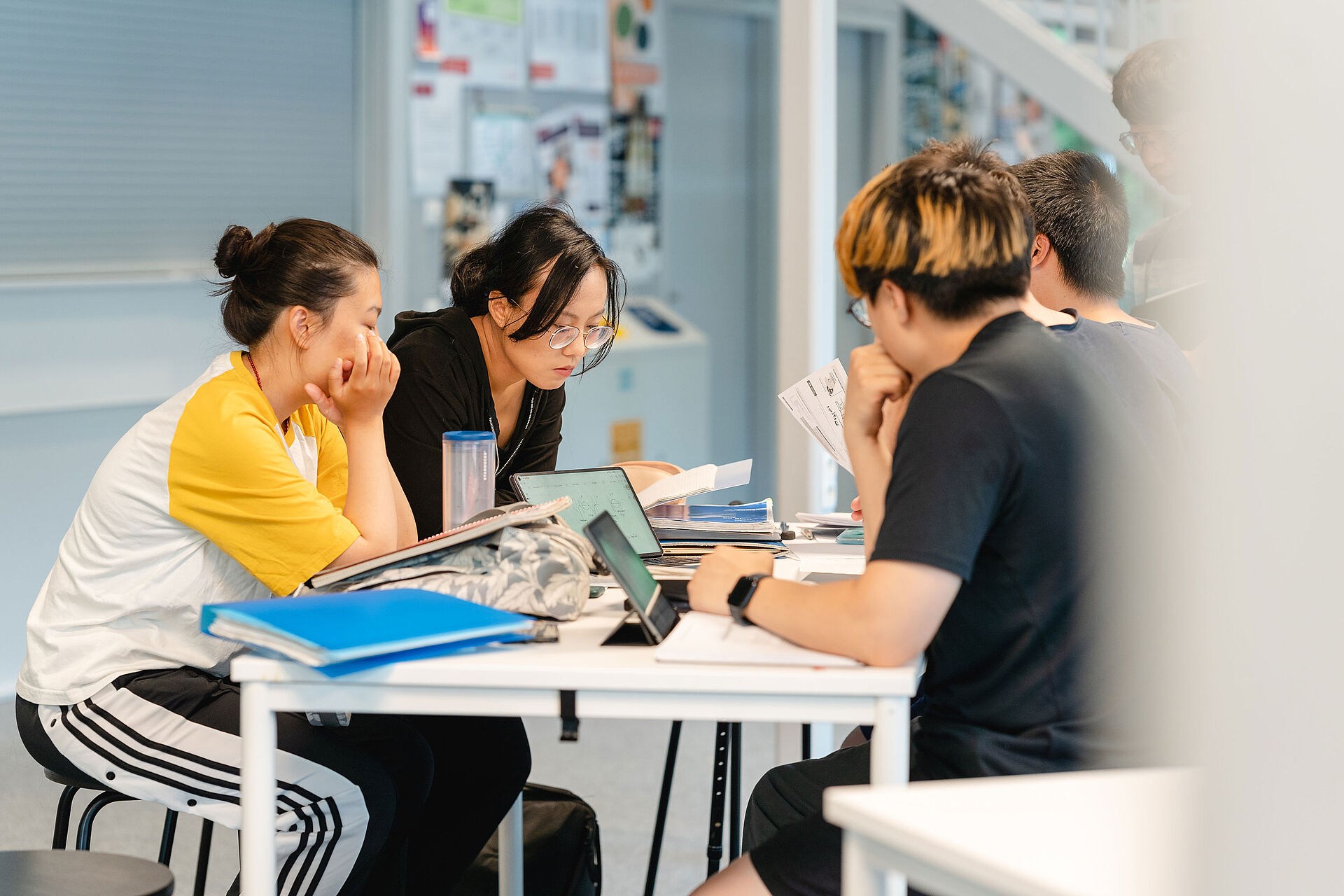 Students sit at a table and learn together.