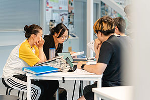 Studierende sitzen an einem Tisch und lernen gemeinsam.