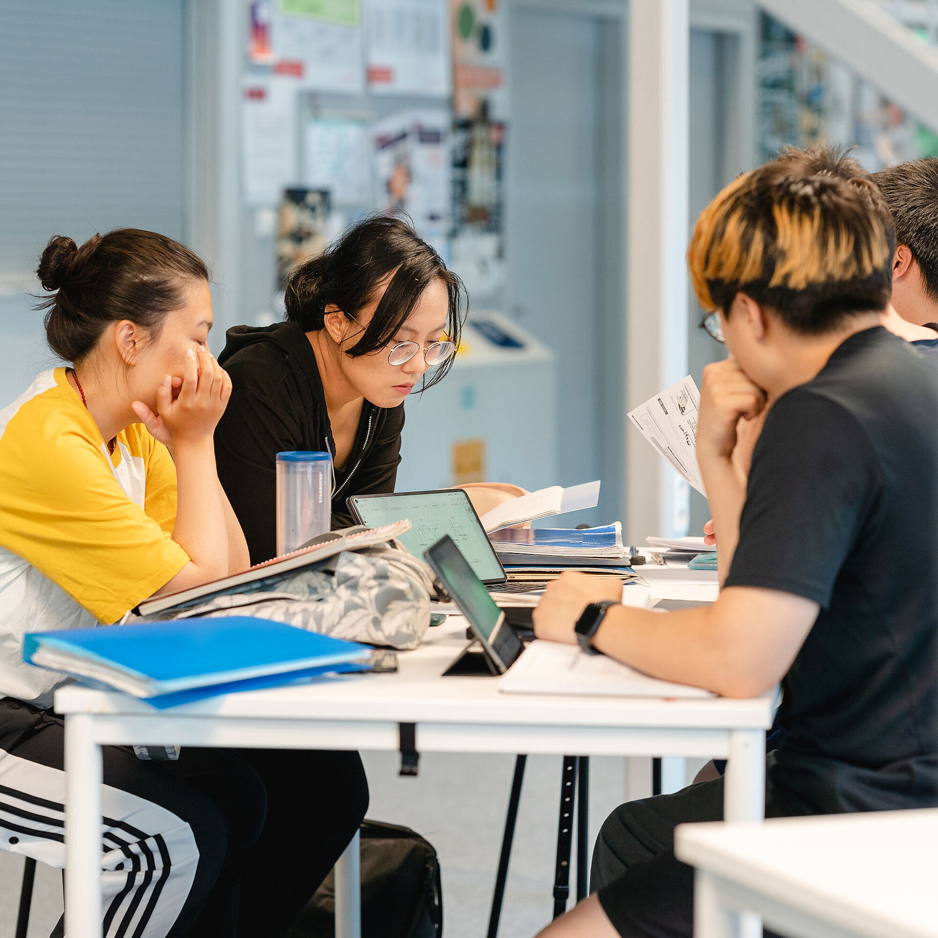 Students sit at a table and learn together.