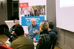 The participants in the panel discussion talk animatedly with each other.