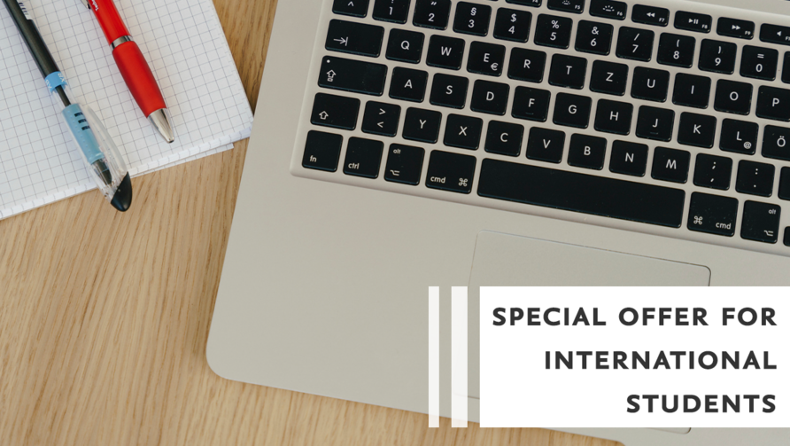 Ein Laptop, ein Notizblock und zwei Stifte liegen im Anschnitt auf einem Laptop. Auf dem Foto steht der Text "Special offer for international students".