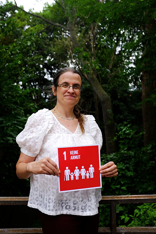 Prof. Dr. Okka Zimmermann hält die Karte zum SDG 1. 