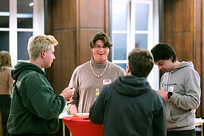 Conference participants stand at a bar table and chat.