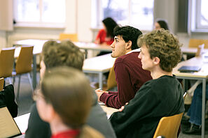 Workshop participants sit in a seminar room and listen intently.