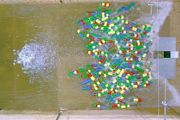 Ein Trümmer-Teppich in Treibgut in Form von farbigen Holzklötzen trifft auf die Säule im Wellenkanal.