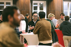 Conference participants stand at a bar table and chat.