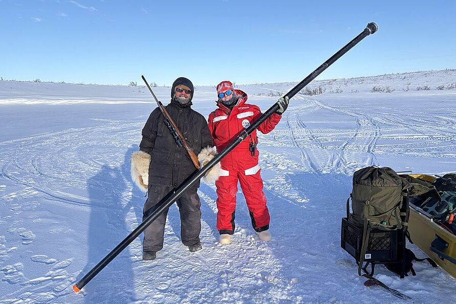 Bei -40 Grad Celsius fror Camerons eigentlicher Sedimentkernbohrer ein. Die Lösung: Ein selbstgebauter Ersatz mit Materialien aus dem lokalen Baumarkt. Neben Cameron steht der einheimische Wildtierbeobachter Miles Dillon. 