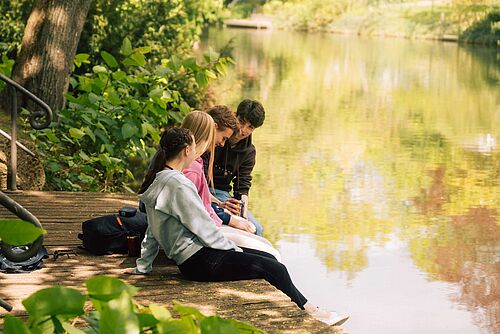 Students are sitting by the River Oker in Braunschweig.
