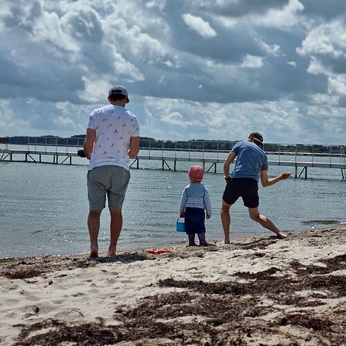 Kind und zwei Männer am Meer