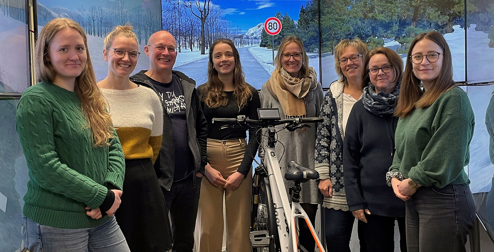 Das Team der Ingenieur- und Verkehrspsychologie vor einer winterlichen Straße im Fahrradsimulator